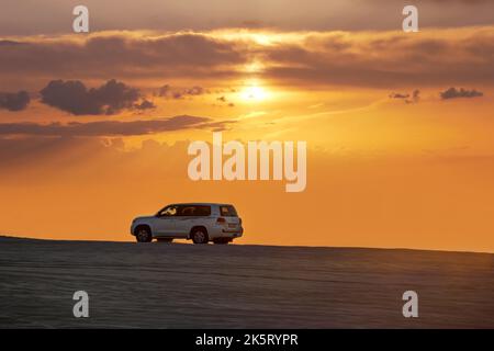 Toyota Landcruiser 4WD en voiture à travers les dunes au coucher du soleil. Ballades dans le cadre d'un safari dans le désert au Qatar Banque D'Images