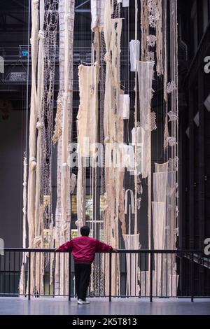 Londres, Royaume-Uni. 10 octobre 2022. Un membre du personnel lors du dévoilement de la Commission Hyundai de cette année dans le hall turbine de Tate Modern par Cecilia Vicuña. L’installation nommée ‘Brain Forest Quipu’ comprend deux sculptures de quipu de 27 mètres de hauteur et poursuit le travail de longue date de l’artiste avec l’ancienne tradition andine du quipu et est en exposition du 11 octobre 2022 au 16 avril 2023. Credit: Stephen Chung / Alamy Live News Banque D'Images