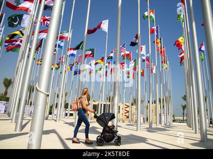 2022-10-05 10:43:22 photo prise le 05 octobre 2022. Une femme passe devant les drapeaux affichés représentant des nations avec des missions diplomatiques accréditées par l'État du Qatar alors qu'elles volent sur le nouveau Flag Plaza à Doha corniche à Doha - Qatar avant la compétition de football de la coupe du monde FIFA 2022. pays-bas hors - belgique hors Banque D'Images