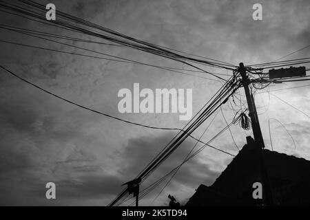 Poteau électrique et toit, Silhouette photo de poteaux électriques pleins de fils derrière le toit d'une maison dans la région de Cikancung, Indonésie Banque D'Images