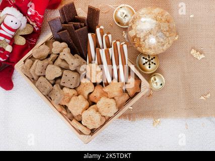 Boîte de Noël en forme de chien dans un cadre de fête rustique avec cloches de jingle Banque D'Images