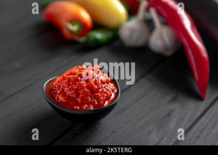 Pâte de piment chaud. Sauce rouge sur fond de bois. Ajika ou ajika dans la cuisine géorgienne ou harissa dans la cuisine arabe. Vue de dessus. Banque D'Images