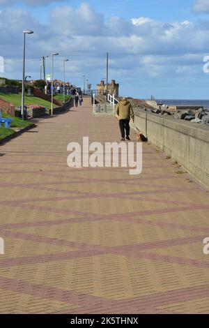Walker avec chien sur la promenade, Withhernsea, East Yorkshire, Sunny, automne, Banque D'Images