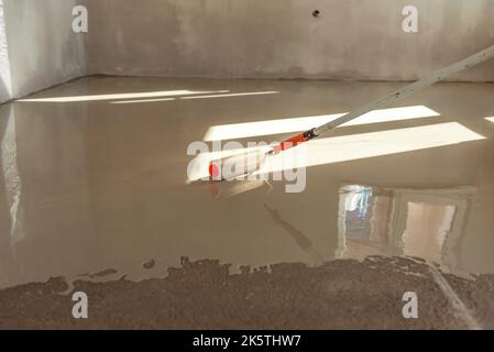 Rouleau à aiguilles pour sols auto-nivelants. Nivellement des sols avec un mélange de ciment. Banque D'Images