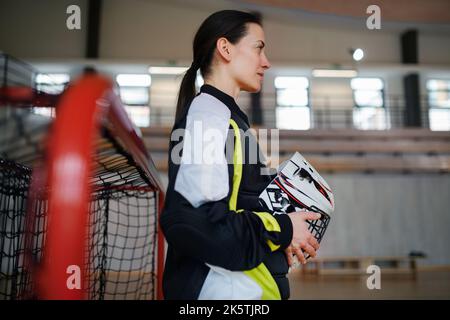 Gros plan de la femme gardien de floorball dans un casque concetating sur le match dans la salle de gym. Banque D'Images