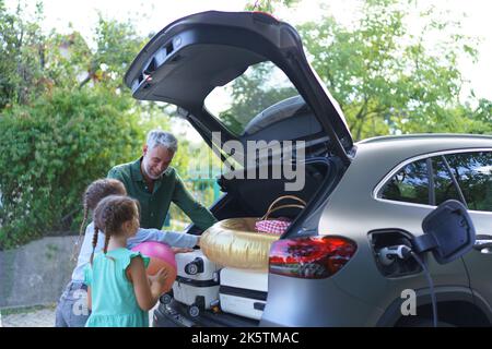 Famille avec de petits enfants qui chargent la voiture et qui attendent de charger la voiture avant de commencer le pique-nique. Banque D'Images