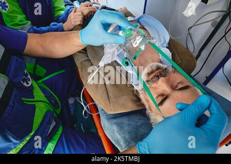 Ambulanceman mettant le masque d'oxygène sur le patient en ambulance pendant le voyage à l'hôpital. Transport en ambulance et premiers soins Banque D'Images