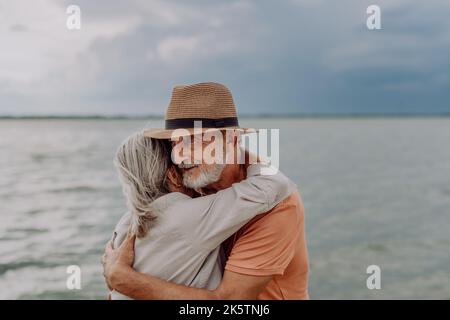 Couple senior amoureux s'embrassant les uns les autres, ayant un moment romantique près de la mer d'automne. Banque D'Images