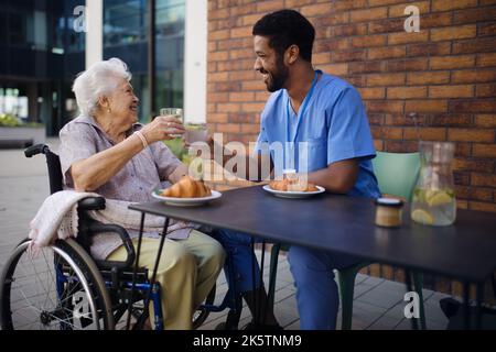 Soignant prenant le petit déjeuner avec son client au café. Banque D'Images
