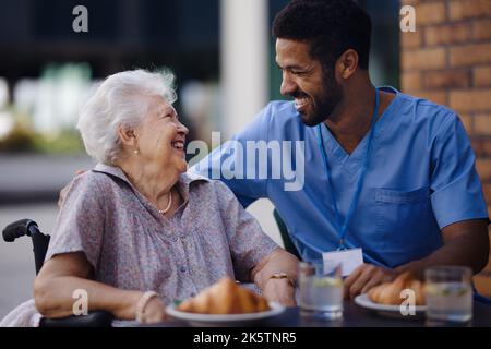 Soignant prenant le petit déjeuner avec son client au café. Banque D'Images
