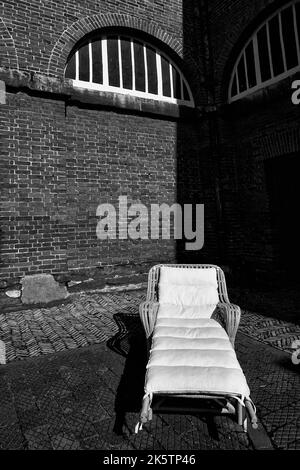 chaise de jardin relaxante dans la cour en brique formelle de grande maison de campagne Banque D'Images