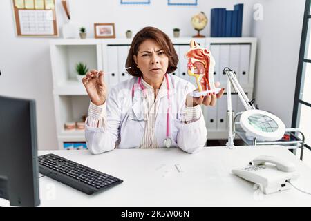 Âge moyen médecin hispanique femme tenant une infection à coronavirus test nasal expression sans indice et confuse. Notion de doute. Banque D'Images