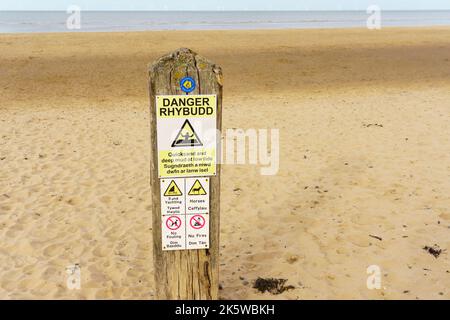 Panneau d'avertissement en anglais et en gallois sur une plage qui conseille les baigneurs de sable blanc et de boue profonde sur la plage de Talaacre au nord du pays de Galles Banque D'Images