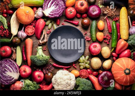Assiette noire sur la table avec fruits et légumes, récolte d'automne frais sur fond de bois rustique vue du dessus. Assortiment de légumes pour la santé Banque D'Images