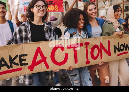 Démonstration du climat chez les jeunes. Des jeunes dynamiques tiennent une bannière tout en marchant contre le changement climatique. Activistes multiculturels de la jeunesse de campagne pour Banque D'Images