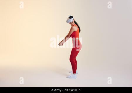 Bonne jeune femme jouant au golf en réalité virtuelle. Jeune femme gaie balançant un club de golf virtuel utilisant des contrôleurs de jeu. Sportswoman portant un v Banque D'Images