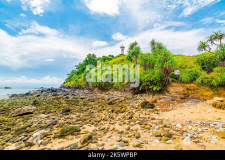 Phare sur le rocher au parc national de Mu Ko Lanta, Thaïlande. Vue de la plage avec pierres. Météo d'été, ciel bleu avec nuages. Banque D'Images