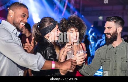 Des jeunes amis multiraciaux dansant dans la boîte de nuit - des gens heureux qui s'amusent à la boîte de nuit après la fête - concept de vie nocturne ivre avec un gars de l'après-fête Banque D'Images