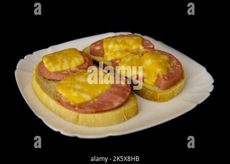 Sandwichs avec saucisse et fromage isolés sur le noir. Banque D'Images