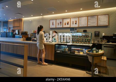 Jeune femme passant une commande au comptoir d'un café Starbucks à Vancouver, C.-B., Canada Banque D'Images