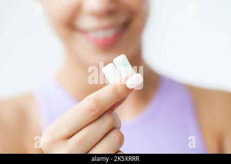 Sourire jeune femme mangeant de la gomme à mâcher blanche Banque D'Images