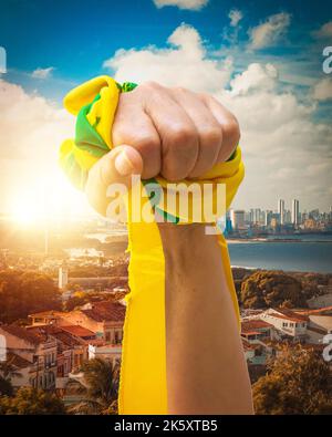 Tenant des rubans verts et jaunes du drapeau brésilien isolés sur fond de ville. Banque D'Images