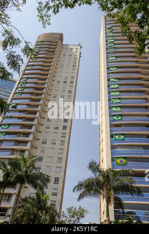 Goias, Brésil – 28 septembre 2022 : deux bâtiments résidentiels avec plusieurs drapeaux brésiliens sur les fenêtres. Banque D'Images