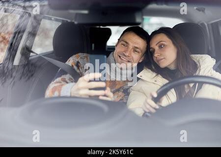 Portrait d'un couple d'adultes heureux prenant le selfie en voiture ensemble et appréciant les vacances d'hiver Banque D'Images