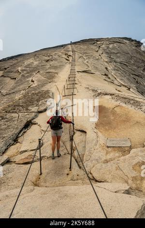 Une femme de randonnée commence à monter les câbles sur Half Dome à Yosemite Banque D'Images