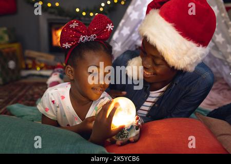 Bonne mère et fille afro-américaine couchée à la tipi et jouant Banque D'Images