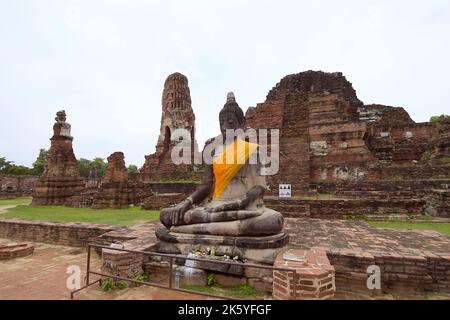 Image de Bouddha partiellement restaurée dans la terre touchant la pose, assise devant les ruines du prang central, Wat Mahathe, Parc historique d'Ayutthaya Banque D'Images