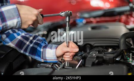 Mécanique automobile femelle en dévissant un écrou pour remplacer une bougie d'allumage de voiture. Banque D'Images