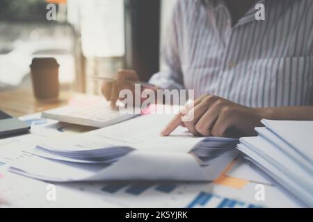 Femme d'affaires utilisant la calculatrice pour le budget de finances d'audit sur le bureau en bois dans le bureau, la fiscalité, la comptabilité, les statistiques et le concept de recherche analytique Banque D'Images