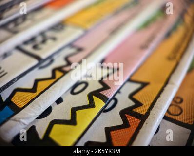 La vue en gros plan d'une ancienne collection de bandes dessinées empilées dans un tas crée une texture de papier d'arrière-plan colorée avec des formes abstraites Banque D'Images