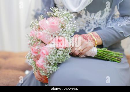 Main de mariée avec henné et un bouquet de fleurs Banque D'Images