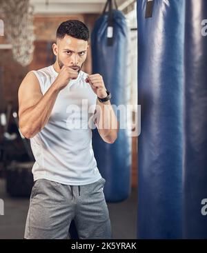 Boxer résistant prêt à frapper dans la salle de gym. Portrait du combattant mma prêt pour le combat cardio. Boxer s'y portant avec un sac de poinçonnage. Bodybuilder à l'aide de Banque D'Images