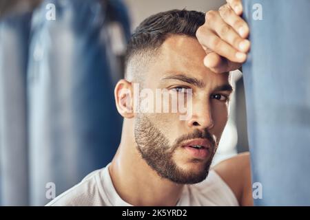 Boxeur fatigué prenant une pause de la routine cardio. Portrait d'un combattant mma épuisé appuyé sur un sac de poinçonnage. Bodybuilder prend une pause de combat Banque D'Images
