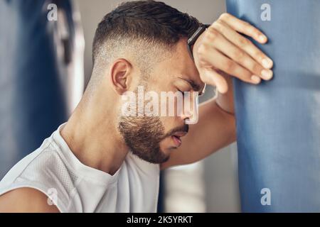 Caleçon épuisé après la routine d'entraînement. Combattant mma fatigué prenant une pause de la routine d'exercice. Combattant de combat penché sur le sac de poinçonnage. Fort Banque D'Images