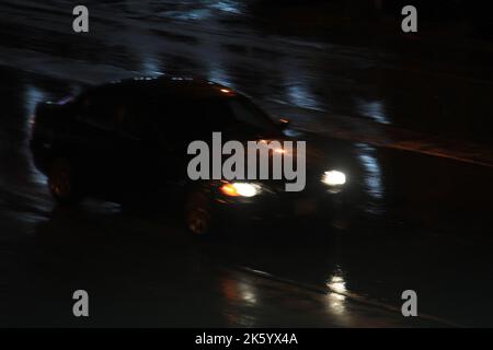 Une voiture floue qui s'emballe avec des sentiers de queue lors d'une nuit de pluie. Banque D'Images