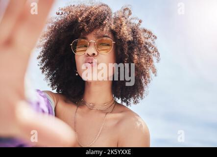 Portrait d'une jeune femme de race mixte à la mode avec un afro souriant et posant pour un selfie à l'extérieur. Femme hispanique portant des lunettes de soleil Banque D'Images
