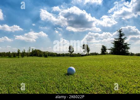 Herbe verte luxuriante du terrain de club d'or sous le ciel bleu avec boule blanche sur le sol Banque D'Images