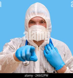 Homme médecin medic dans un uniforme de costume de protection avec des lunettes et un masque facial sur un fond bleu studio.Paramédic en vêtements de protection antiviral blancs Banque D'Images