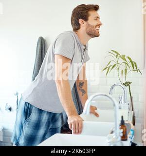 Un bel homme qui vérifie ses dents dans une salle de bains à la maison. Homme caucasien nettoyant ses dents et regardant dans un miroir dans son appartement. Banque D'Images