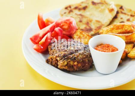 Hamburger de style grec avec pommes de terre cuites au four, sauce au poivre grillé, tomates et pain pita (sélection) Banque D'Images