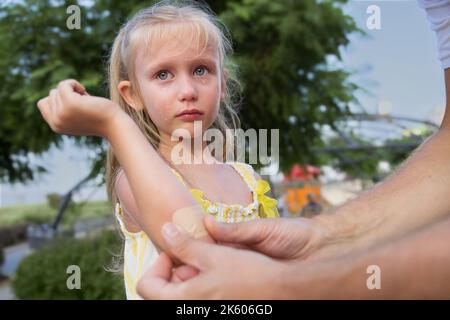 Petite fille. Blessure au coude. Tombé dans le parc lors d'une promenade, montre une blessure et des cris Banque D'Images