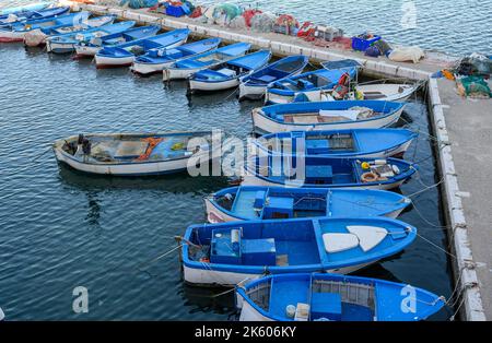 Des rangées de petits bateaux de pêche peints en bleu et blanc amarrés à une jetée dans le port des pêcheurs, dans le port de Gallipoli, à Pouilles (Italie). Banque D'Images