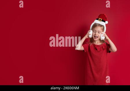 Longue bannière. Fille dans les vêtements de noël, surprise et rire sur un fond rouge Banque D'Images