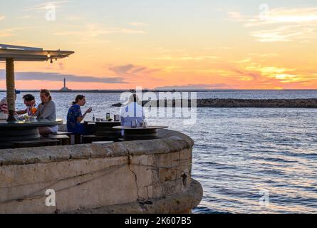 Les personnes qui apprécient la nourriture et les boissons au restaurant en plein air Buena Vista sur le bord de mer médiéval rempart dans la vieille ville de Gallipoli, Apulia (Puglia), Italie. Banque D'Images