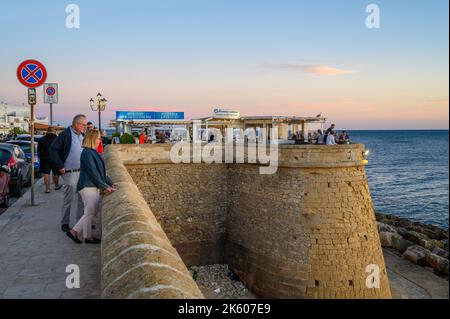 Les personnes qui apprécient la nourriture et les boissons au restaurant en plein air Buena Vista sur le bord de mer médiéval rempart dans la vieille ville de Gallipoli, Apulia (Puglia), Italie. Banque D'Images