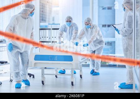 Une équipe de biorisques qui recueille un corps mort de l'hôpital. Spécialistes médicaux travaillant dans une zone interdite de l'hôpital. Médecins travaillant derrière un ruban de mise en garde Banque D'Images